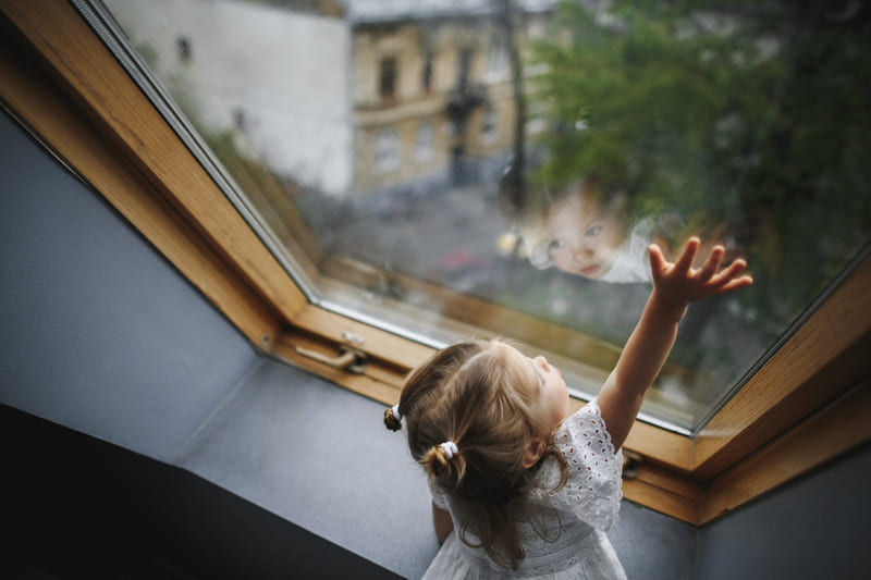 petite fille regardant par une fenêtre de toit Velux à Saint Gaudens